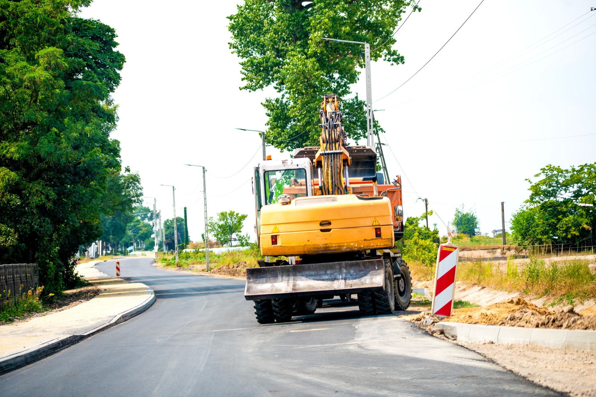 Yellow construction machines on the road with an excavator